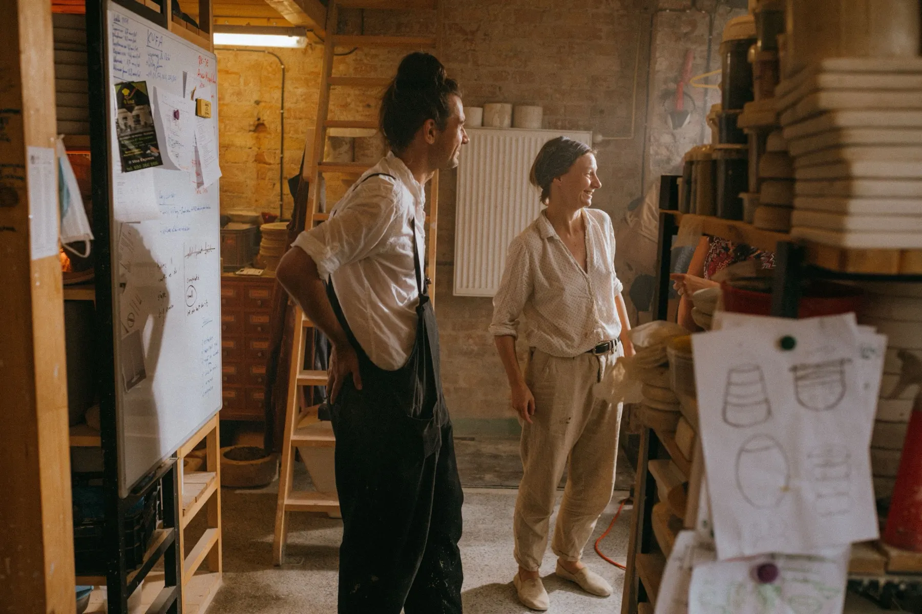Two ceramic studio operators reviewing work beside a production table