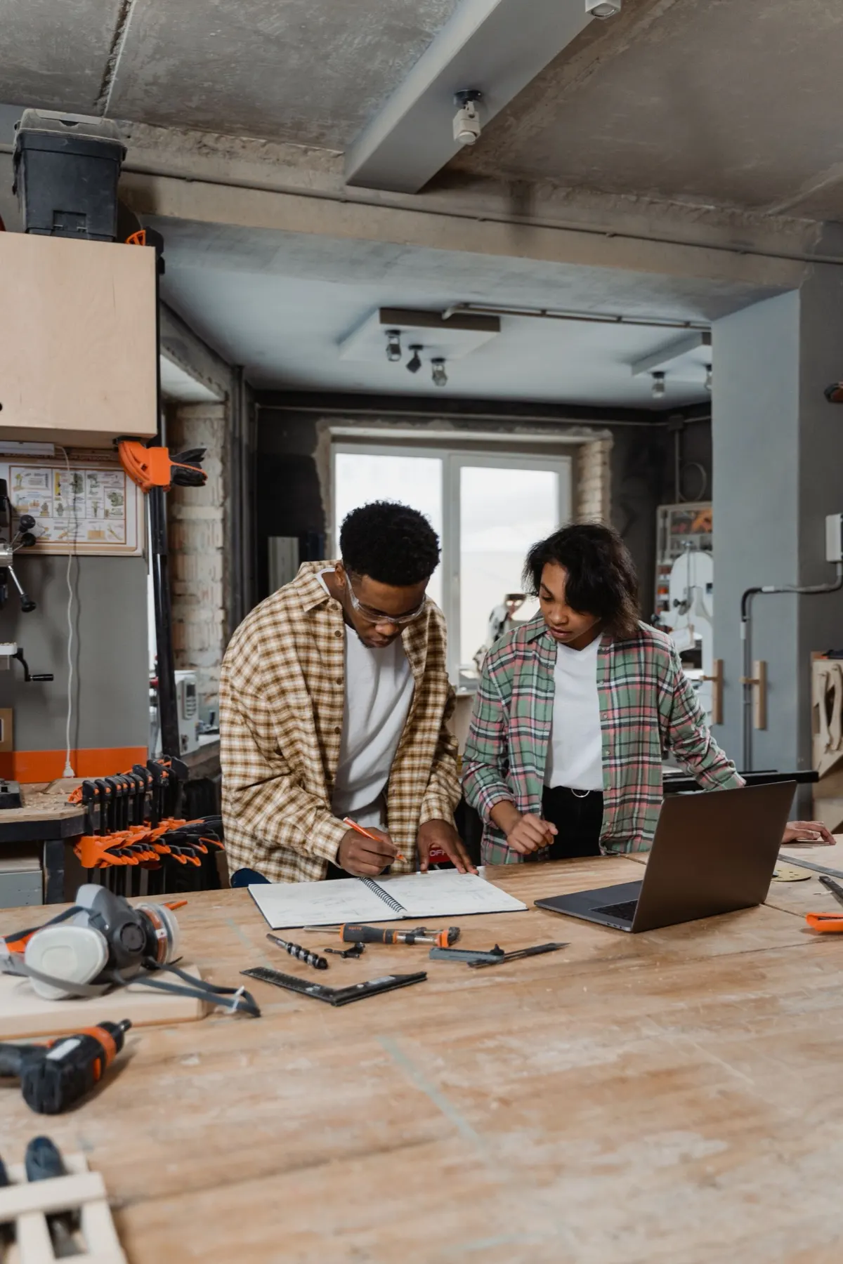 Two makers reviewing a work plan beside tools in a small workshop